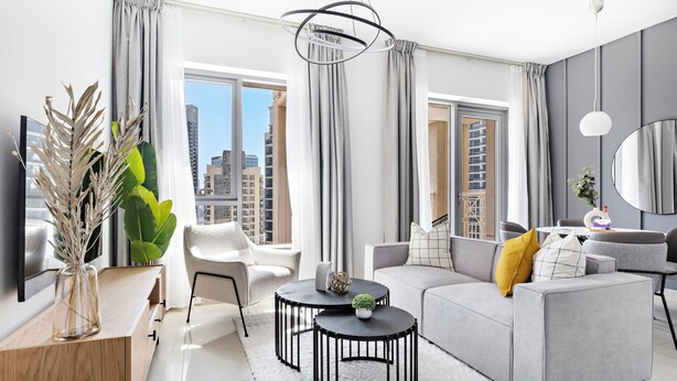 A modern living room with a grey sofa, a round coffee table, and a large window with curtains. - Silkhaus 29 Boulevard, Downtown Dubai (Dubai)