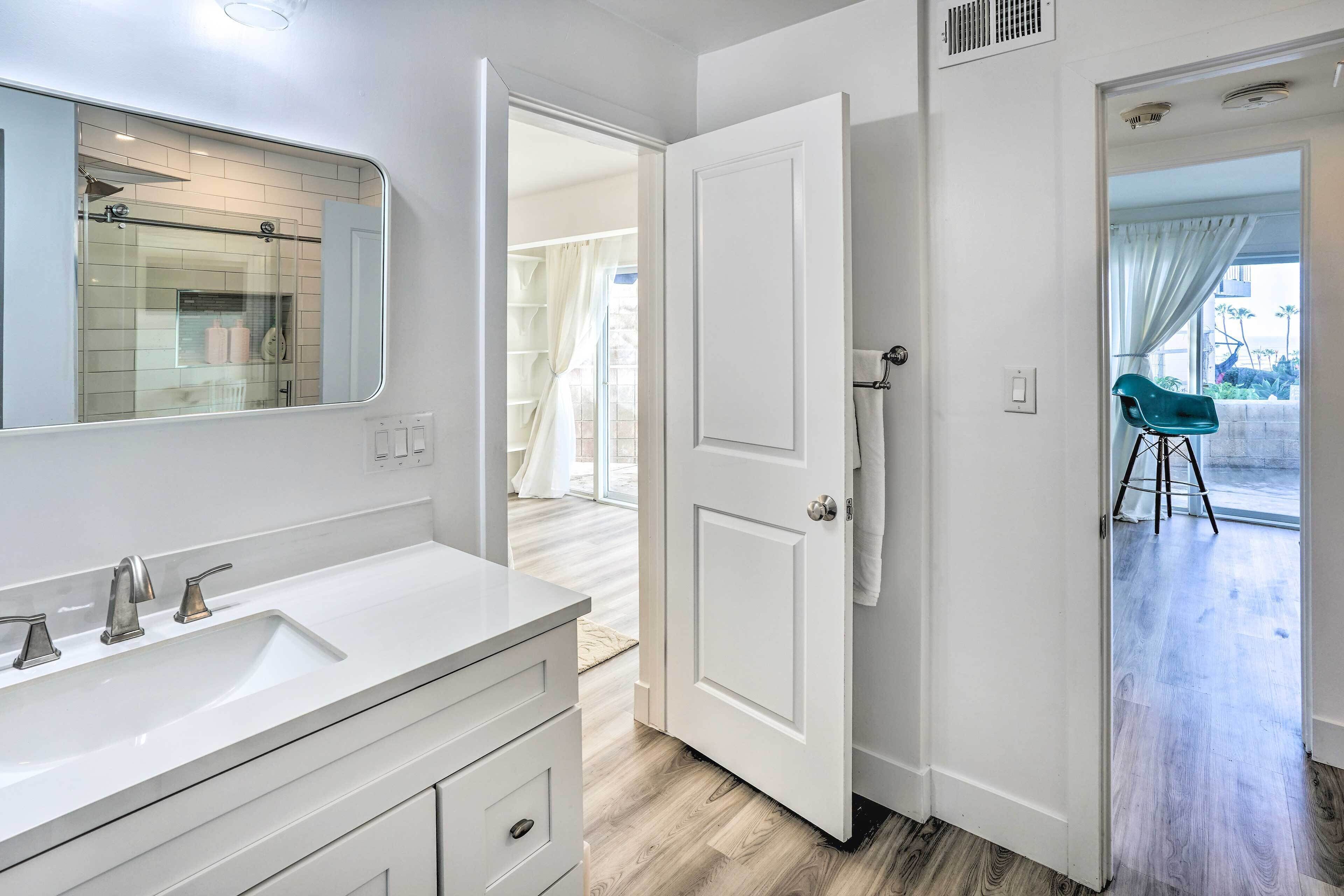 A bathroom with a white vanity, a large mirror, and a glass shower enclosure.