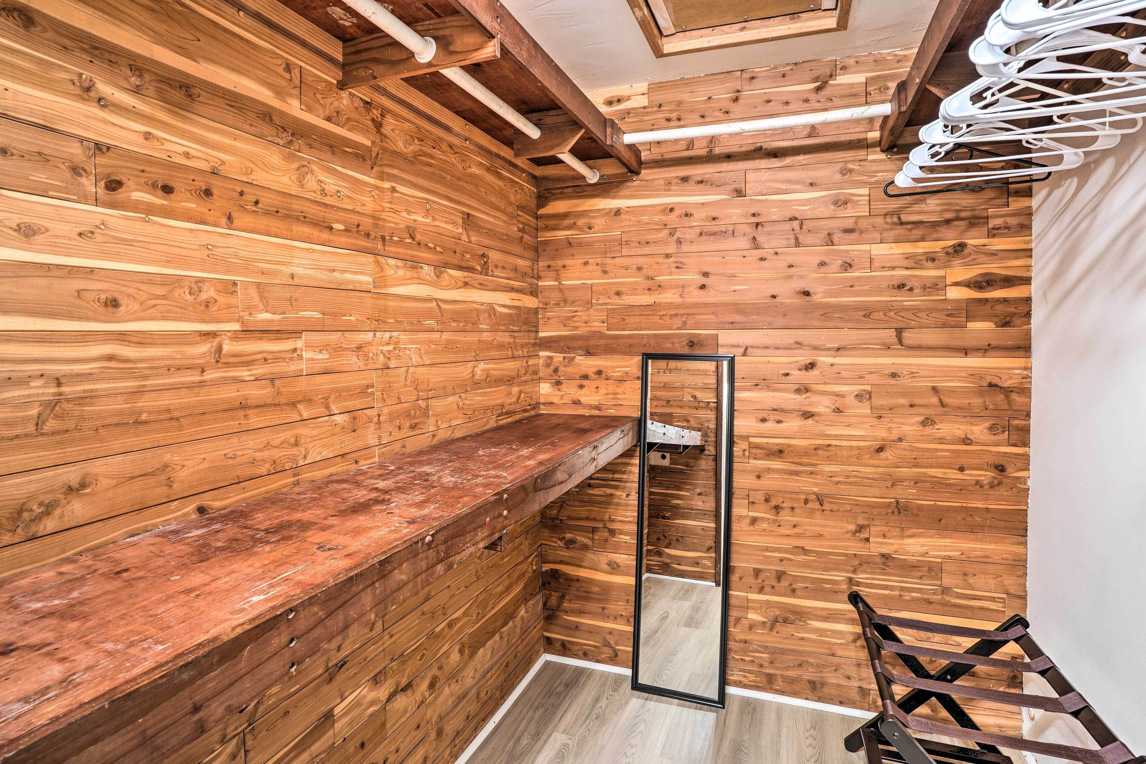 A wooden-paneled room with a wooden bench, a mirror, and a drying rack.