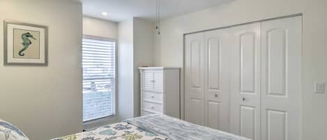 Une chambre à coucher avec un lit, un ventilateur de plafond, une fenêtre avec des stores et une armoire blanche.