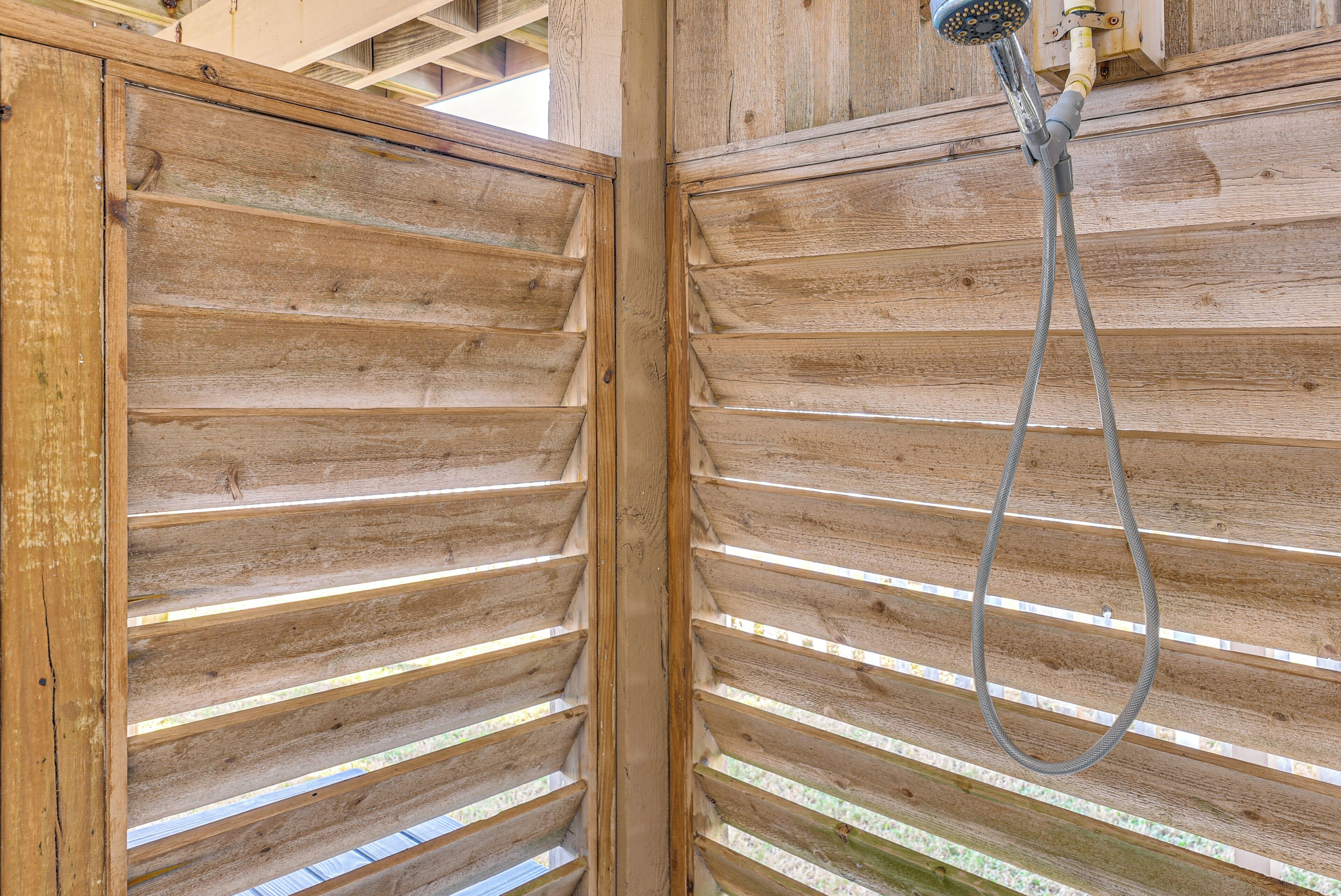 L’intérieur d’un chalet en bois comprend un espace douche avec un mur en lattes de bois et un pommeau de douche.