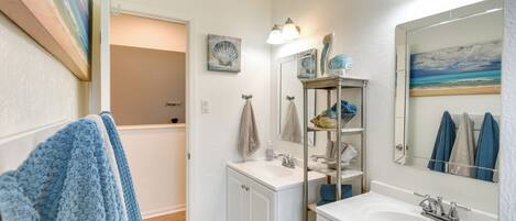 A bathroom with a white vanity, a large mirror, and a shower area.