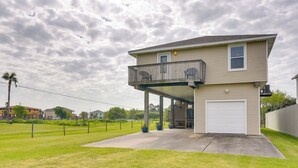 A two-story house with a balcony, a garage, and a well-maintained lawn. - Furnished Patio & Deck: Galveston Escape! (Galveston)