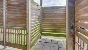 A wooden shower stall with a window, a metal showerhead, and a tiled floor. - Furnished Patio & Deck: Galveston Escape! (Galveston)