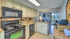 A kitchen with a built-in microwave, stove, and oven, light-colored cabinets, a granite countertop, and a view of the backyard through a sliding glass door. - Gulf Shores Retreat w/ Private Beach Access! (Gulf Shores)