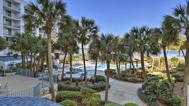 A resort with a pool area surrounded by palm trees and a building with balconies. - Gulf Shores Retreat w/ Private Beach Access! (Gulf Shores)