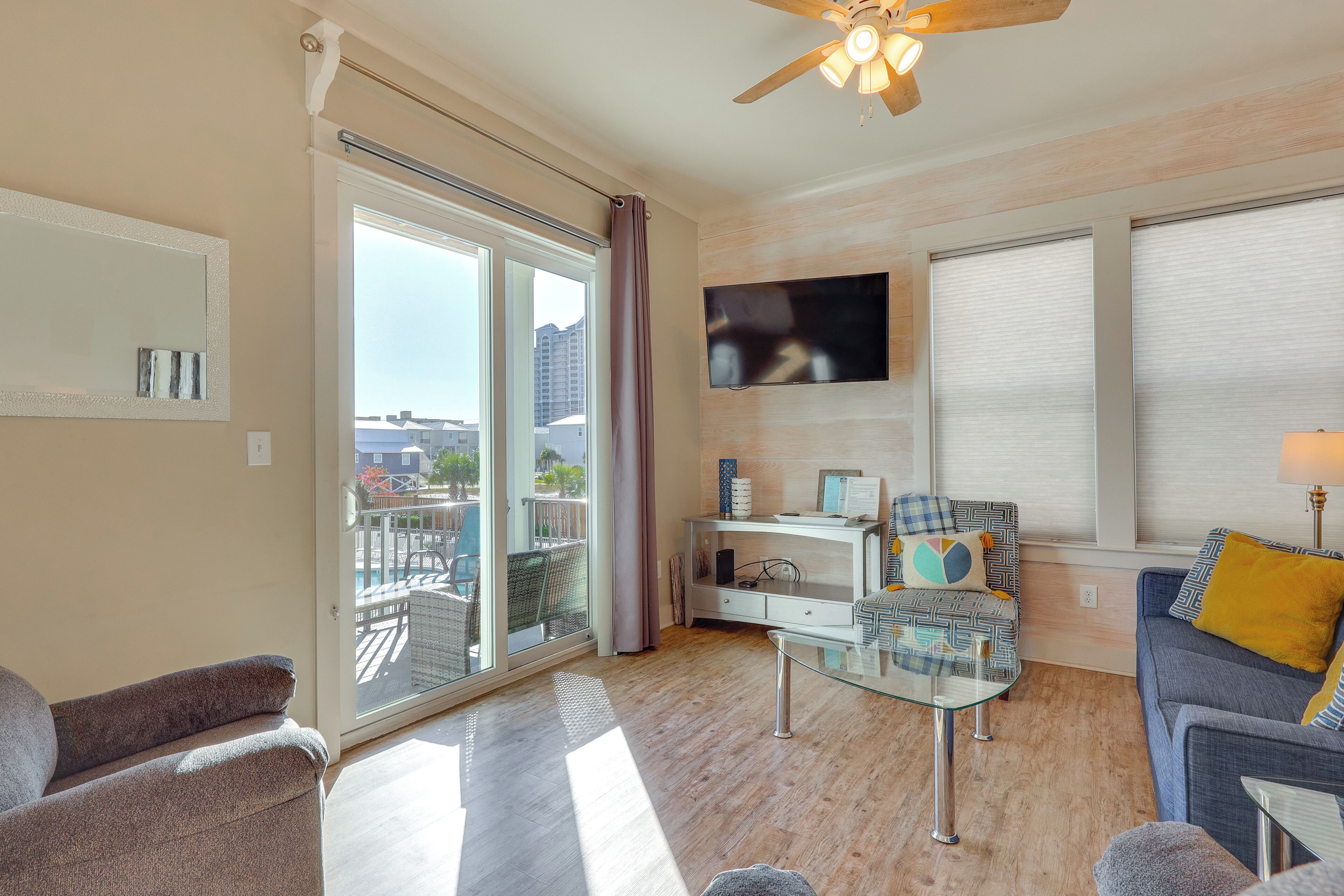 A modern living room with a glass coffee table, a sofa, a chair, and a TV mounted on the wall.