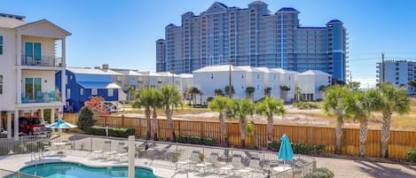 Un hotel con piscina, zona de estar exterior y vista a un edificio alto en el fondo.
