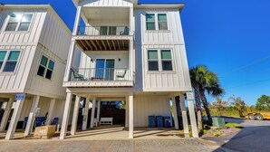 A two-story building with a balcony on the second floor, a covered entrance, and a clear blue sky. - Gulf Shores Home w/ Shared Pool, 2 Blocks to Beach (Gulf Shores)