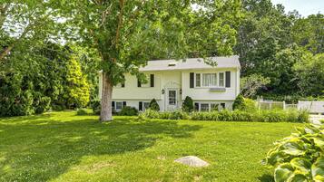 A two-story house with a front porch, surrounded by a well-maintained lawn and trees.
