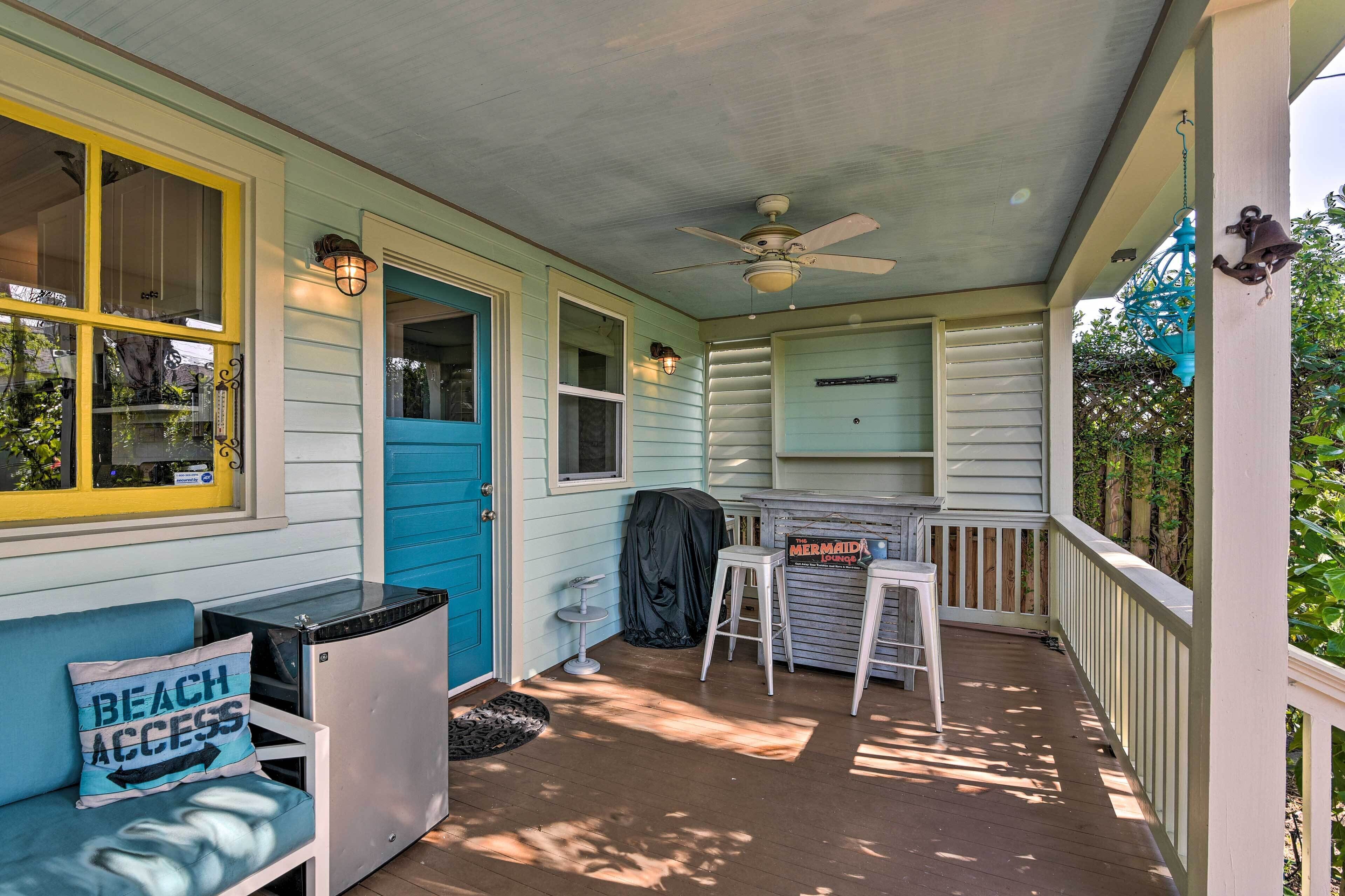A covered porch with a blue door, a white bench, and a small bar area with a sign reading "Mermaid's Paradise."