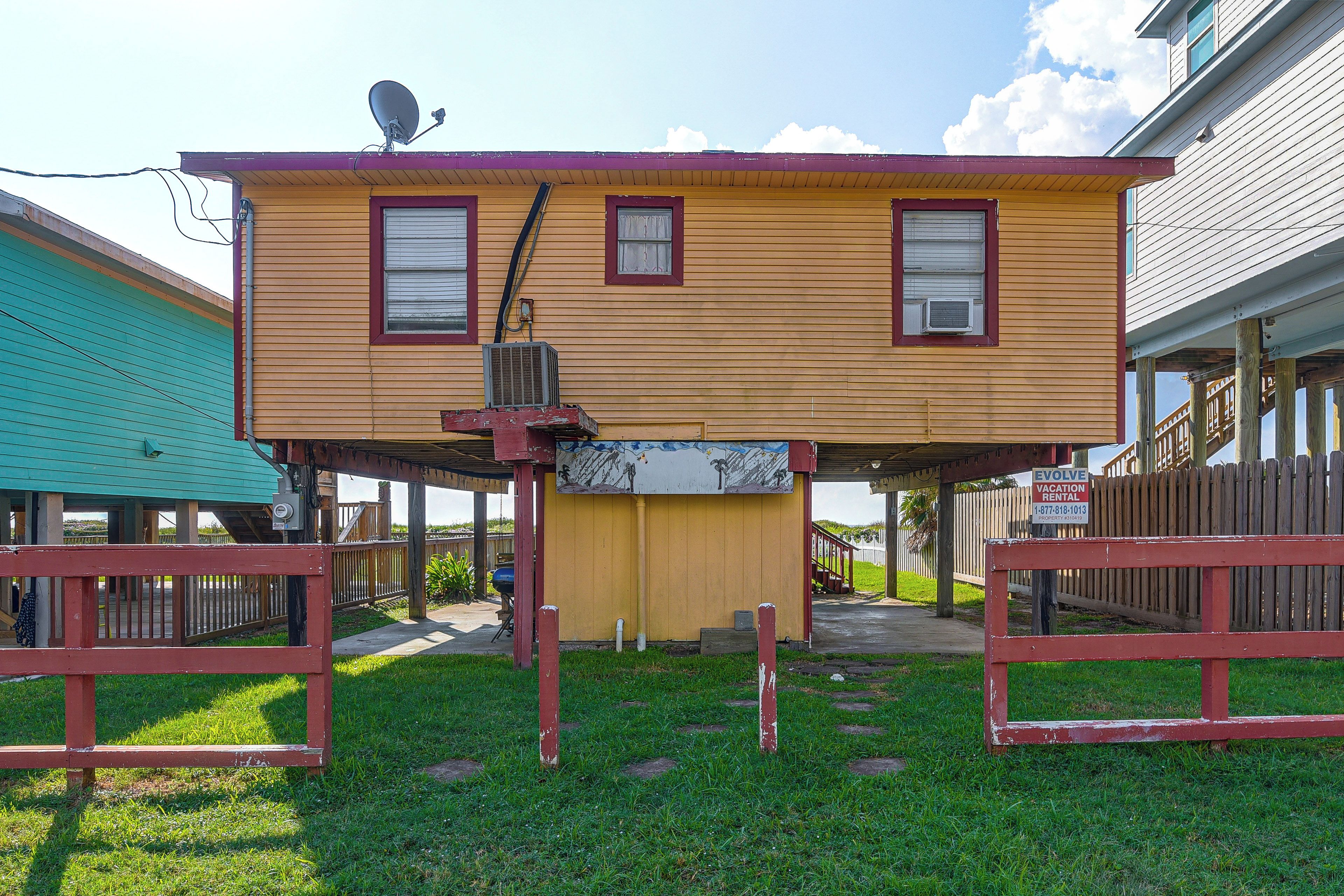 A two-story building with a flat roof, a satellite dish, and a sign advertising vacation rentals.
