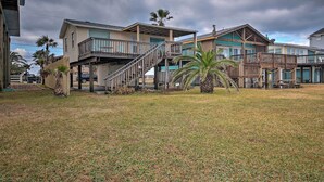 A beachfront property with multiple buildings, including a house with a balcony and a wooden deck. - Steps to Gulf! Pet-friendly Galveston Getaway (Galveston)