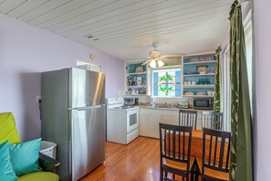 A compact kitchen with a refrigerator, oven, microwave, and a dining area with chairs and a table. - Steps to Private Beach! Pet-friendly Getaway (Galveston)