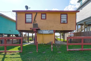A two-story building with a flat roof, a satellite dish, and a sign advertising vacation rentals. - Steps to Private Beach! Pet-friendly Getaway (Galveston)