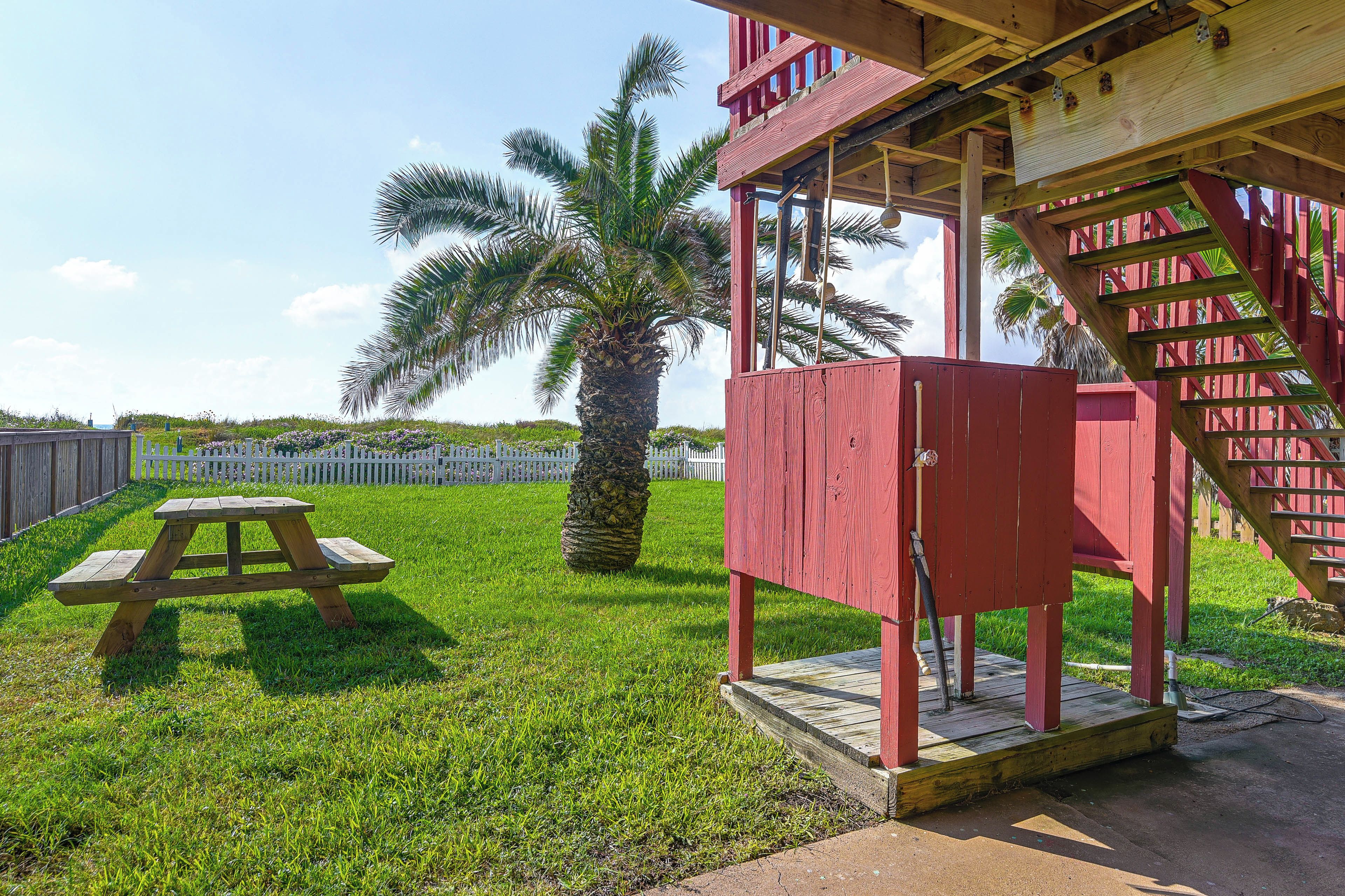 A red wooden structure with a picnic table in a grassy area.