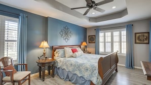 A bedroom with a bed, two bedside tables, a chair, a ceiling fan, and a window with curtains. - Waterfront Lay Lake Retreat w/ Dock & 3 Piers! (Shelby)