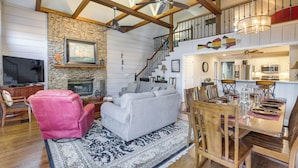 A spacious living room with a fireplace, a dining area with wooden furniture, and a kitchen with modern appliances. - Waterfront Lay Lake Retreat w/ Dock & 3 Piers! (Shelby)