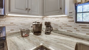 A kitchen with white cabinets, a marble countertop, a Keurig coffee maker, and a glass coffee pot. - Waterfront Lay Lake Retreat w/ Dock & 3 Piers! (Shelby)