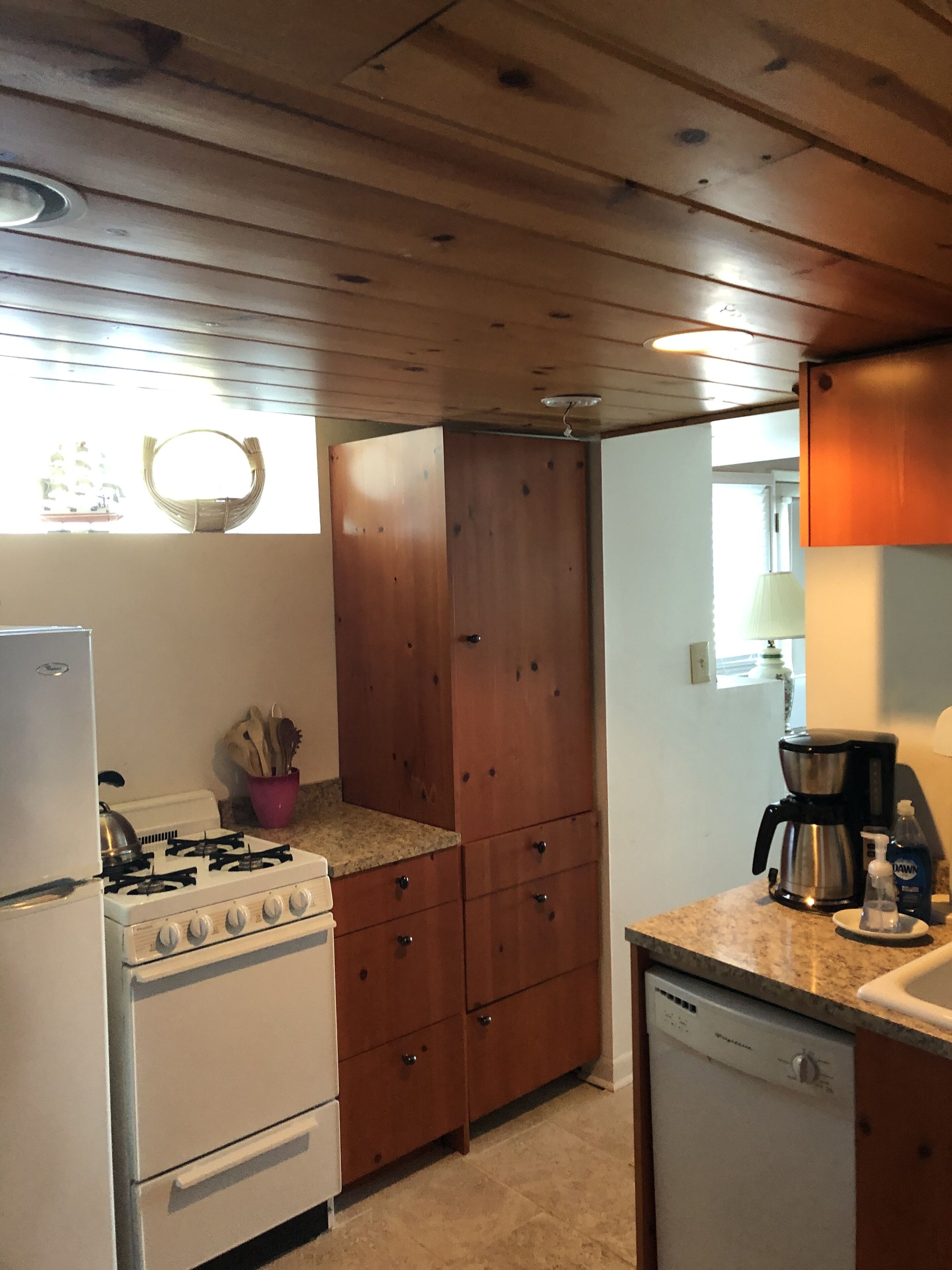 Une cuisine de taille réduite, avec des meubles en bois, une cuisinière blanche et un lave-vaisselle.