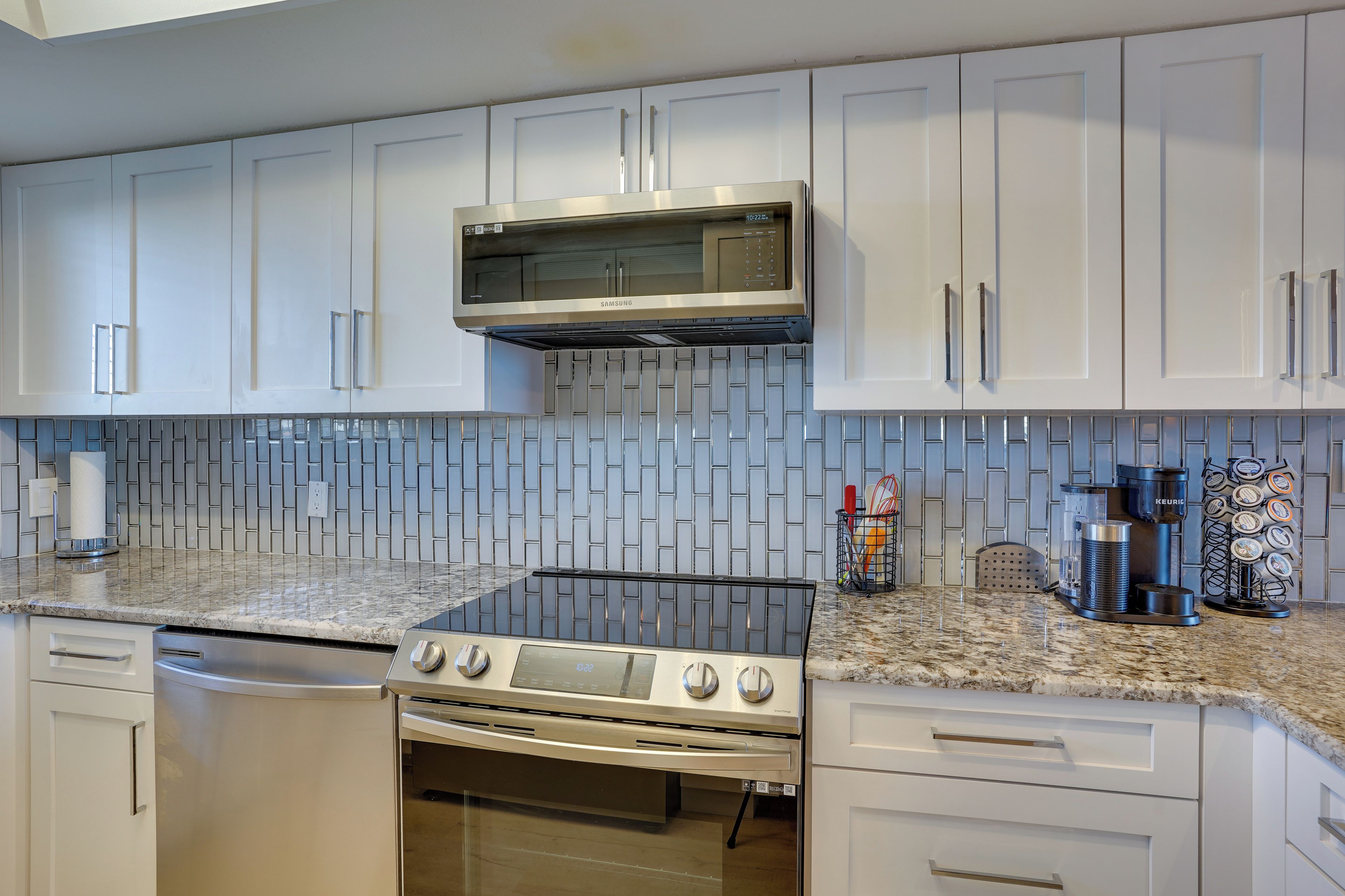 A modern kitchen with white cabinets, a stainless steel microwave, a gas stove, and a built-in oven.