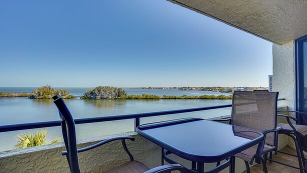 A balcony with a view of a calm body of water, a table, and two chairs. - Cozy Condo w/ Gulf View, Bird Watching + Telescope (Hudson)