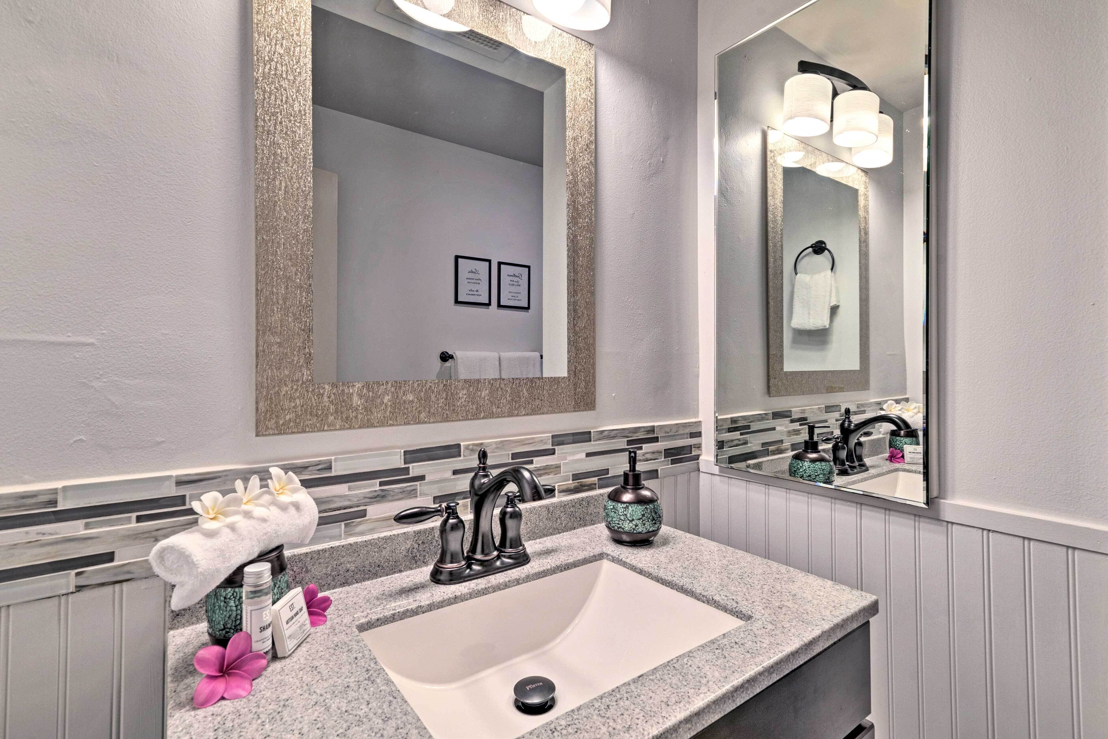 A bathroom with a granite countertop, a sink, a mirror, and a towel rack.