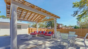 A covered patio area with a sectional sofa, a glass-top table, and chairs. - Gulf Breeze Home w/ Pool, Grill & Fire Pit (Gulf Breeze)