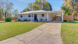A single-story house with a covered porch, a front yard, and a wooden fence. - Gulf Breeze Home w/ Pool, Grill & Fire Pit (Gulf Breeze)