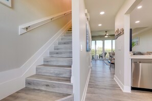 A modern kitchen with a stainless steel dishwasher, a wooden staircase, and a view into the living area. - 1 Mi to Beach: Coastal-zen Ruskin Retreat! (Ruskin)