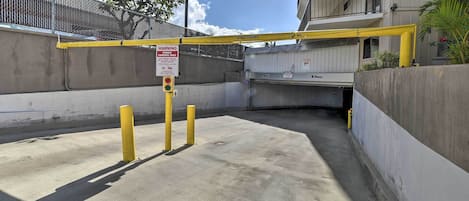 Un espace de stationnement clos par une barrière jaune et agrémenté d’un panneau d’avertissement indiquant les restrictions de stationnement.
