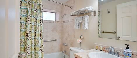 A bathroom with a bathtub, toilet, sink, and a shower curtain.