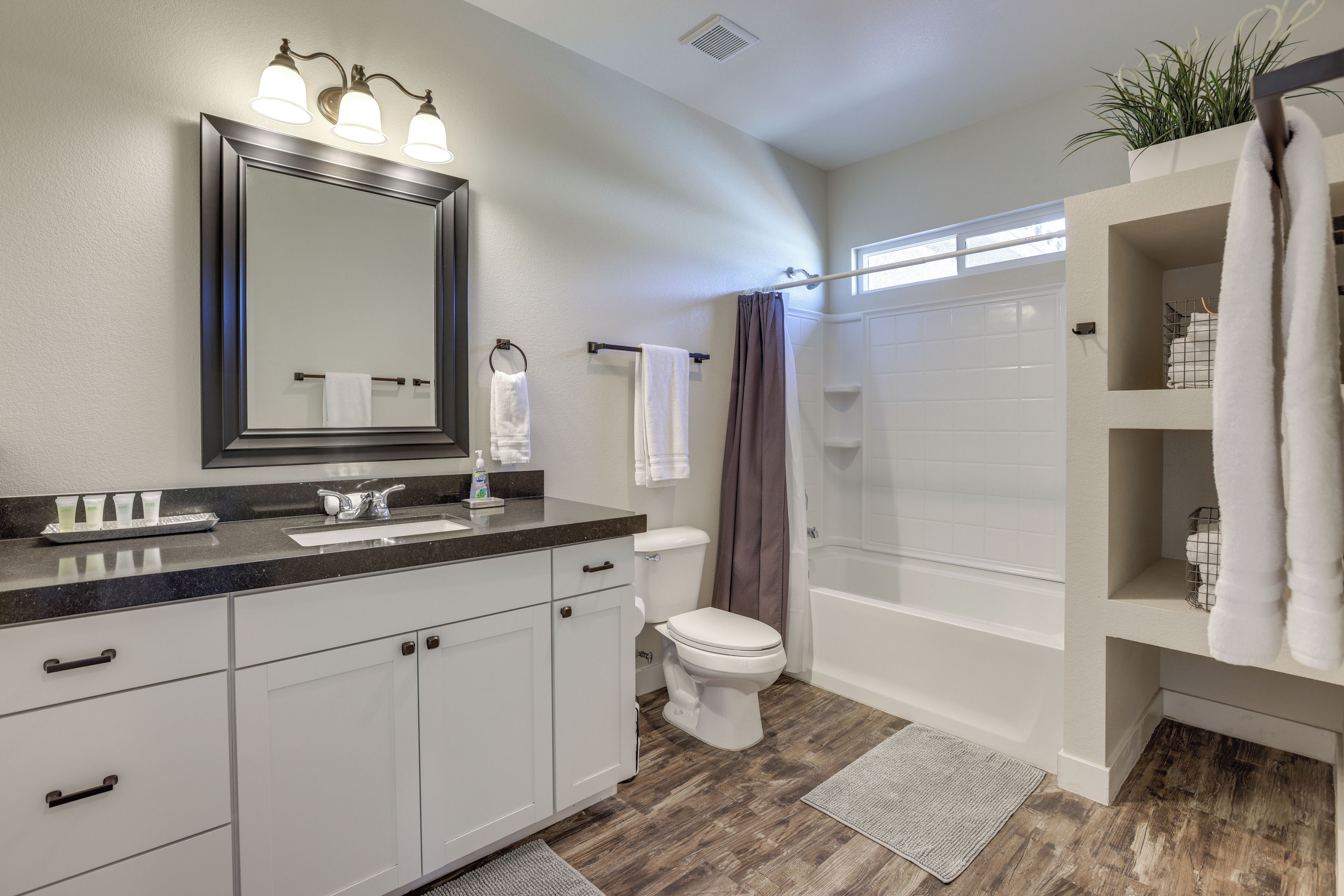 A modern bathroom with a vanity, toilet, shower, and a large mirror.