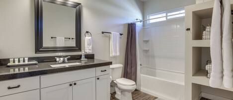 A modern bathroom with a vanity, toilet, shower, and a large mirror.