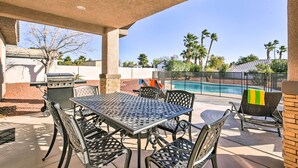 Une terrasse extérieure avec une table et des chaises, un barbecue et une piscine en arrière-plan.