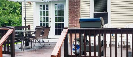 A wooden deck with outdoor furniture, a grill, and a covered patio area.