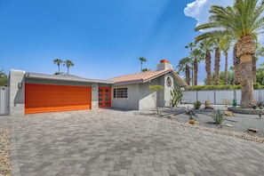A residential property with a red garage door, a stone facade, and a paved driveway.