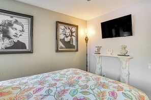A bedroom with a bed, a television mounted on the wall, and a fireplace with decorative items.