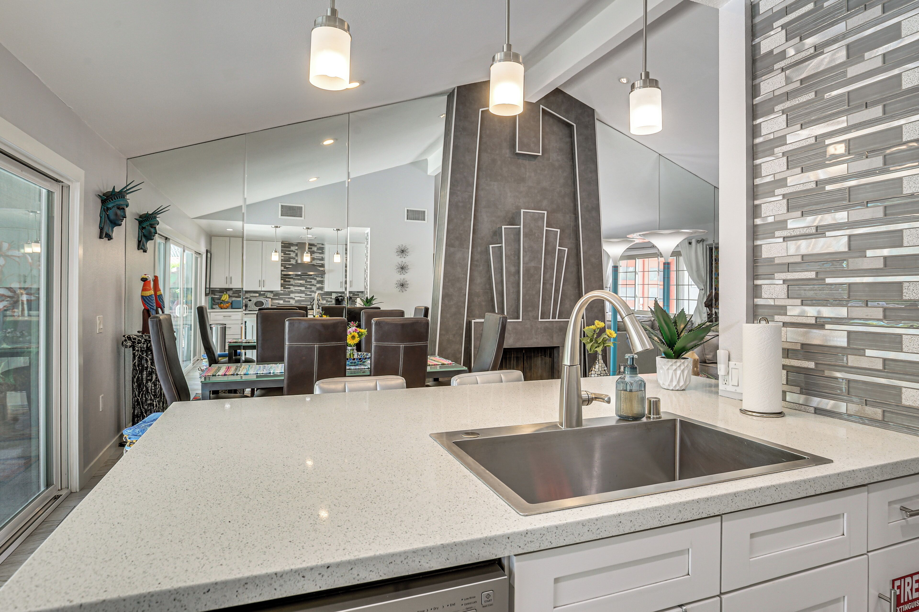 A modern kitchen with a large island, stainless steel appliances, and pendant lighting.