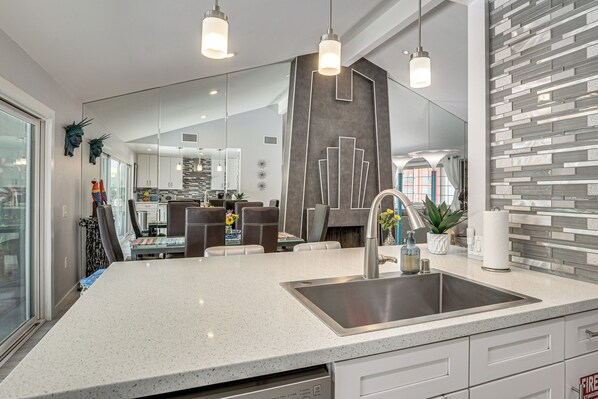 A modern kitchen with a large island, stainless steel appliances, and pendant lighting.