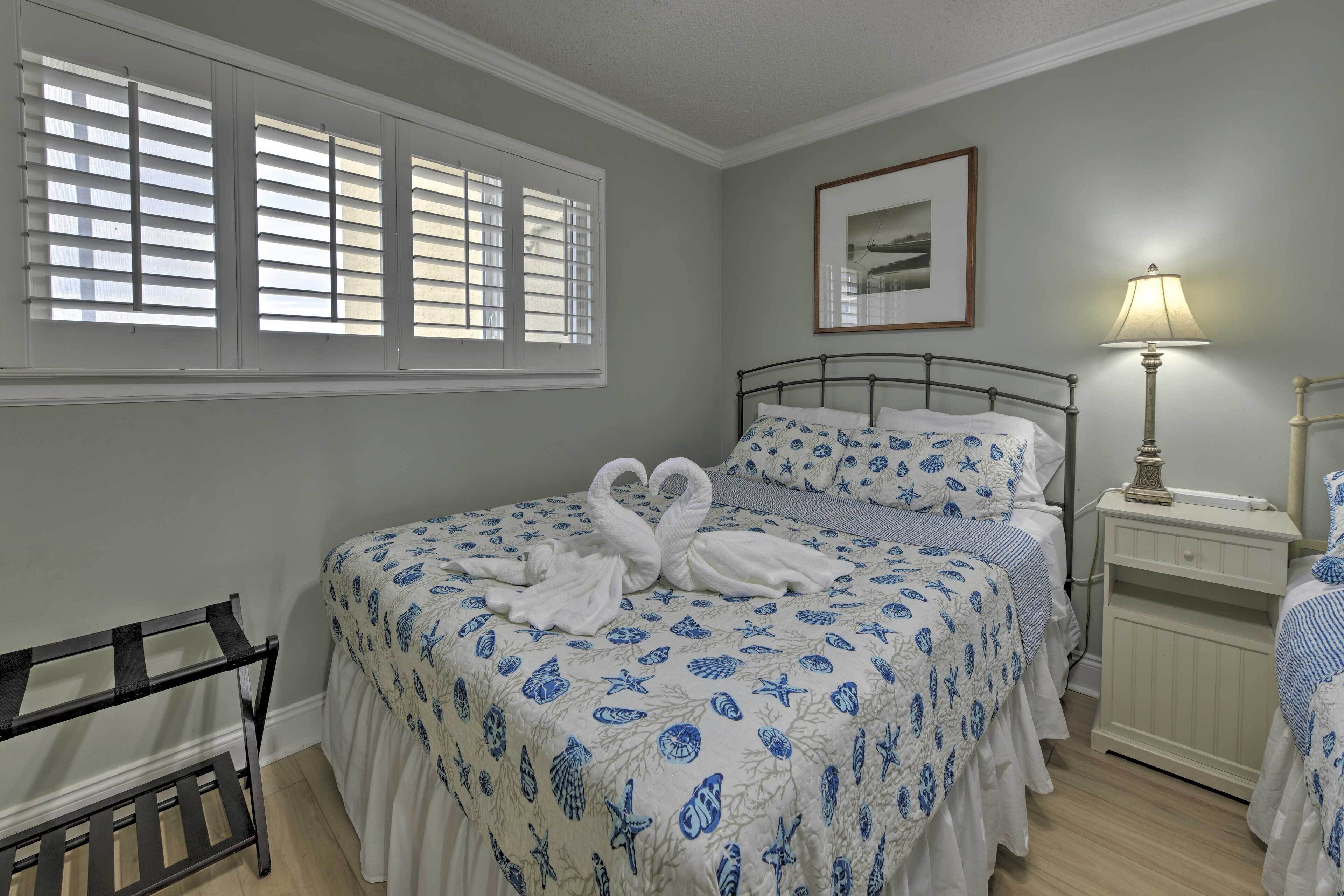 Un dormitorio con cama, mesita de noche, lámpara, silla y ventana con persianas.