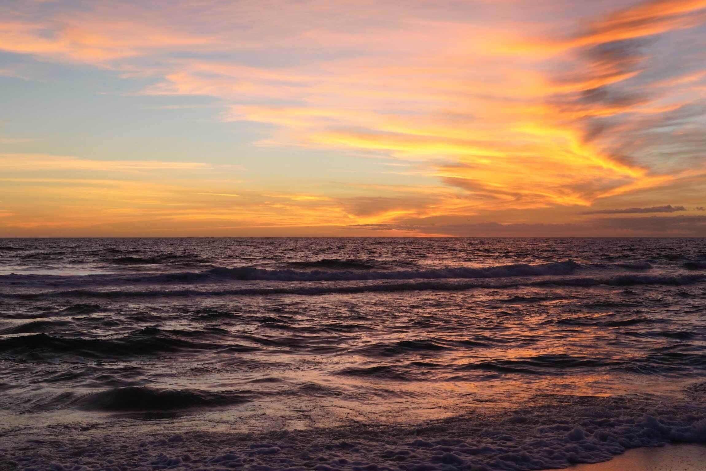 Ein Sonnenuntergang über dem Meer mit Wellen.