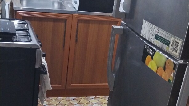 Een keuken met houten kastjes, een roestvrijstalen koelkast, een magnetron en een gasfornuis.