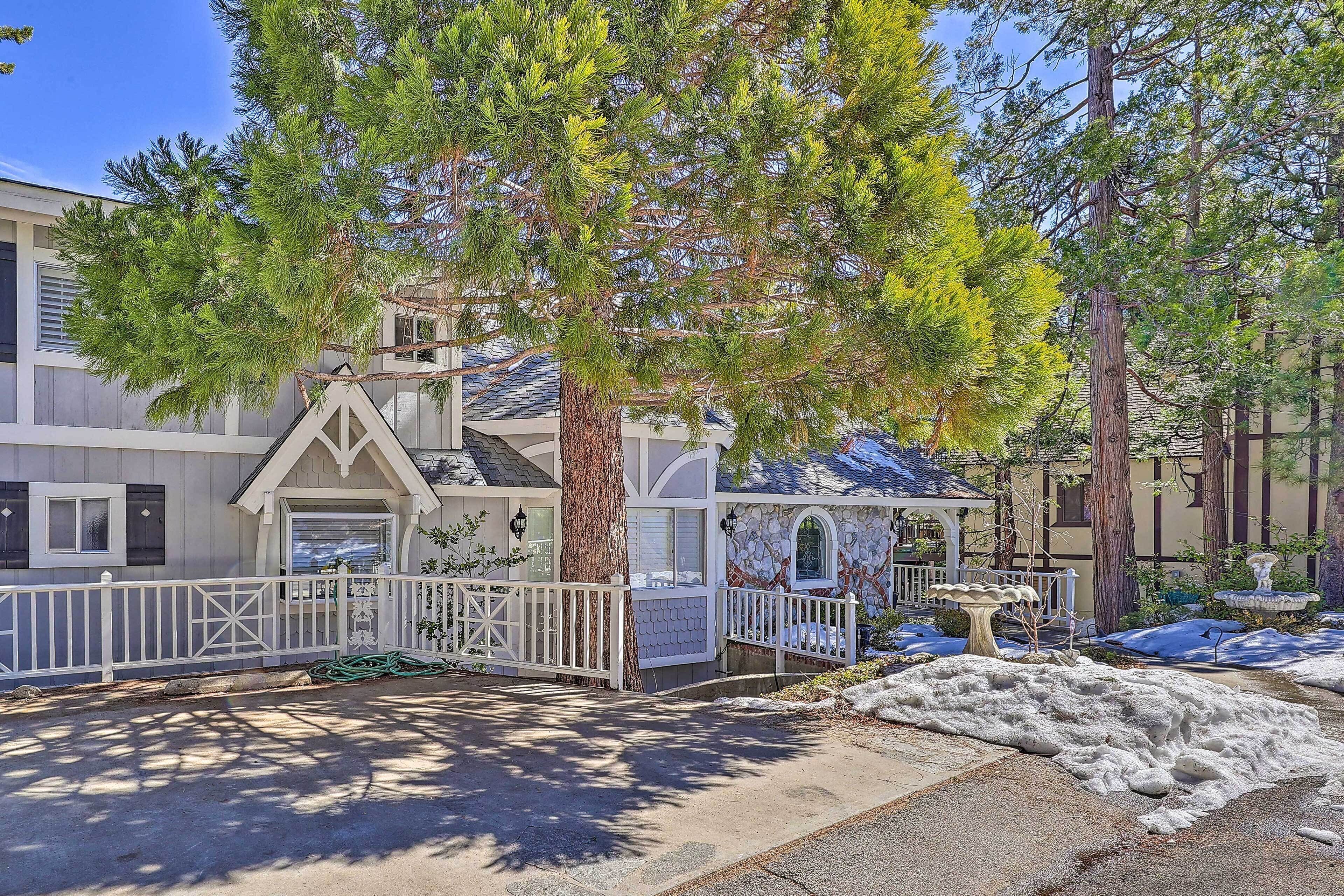 A residential property with a stone facade, a white picket fence, and a snow-covered lawn.