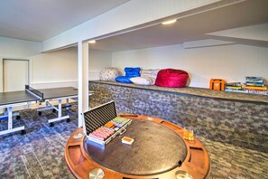 Una mesa de ping pong, pufs y un bar de aperitivos en una habitación de hotel.