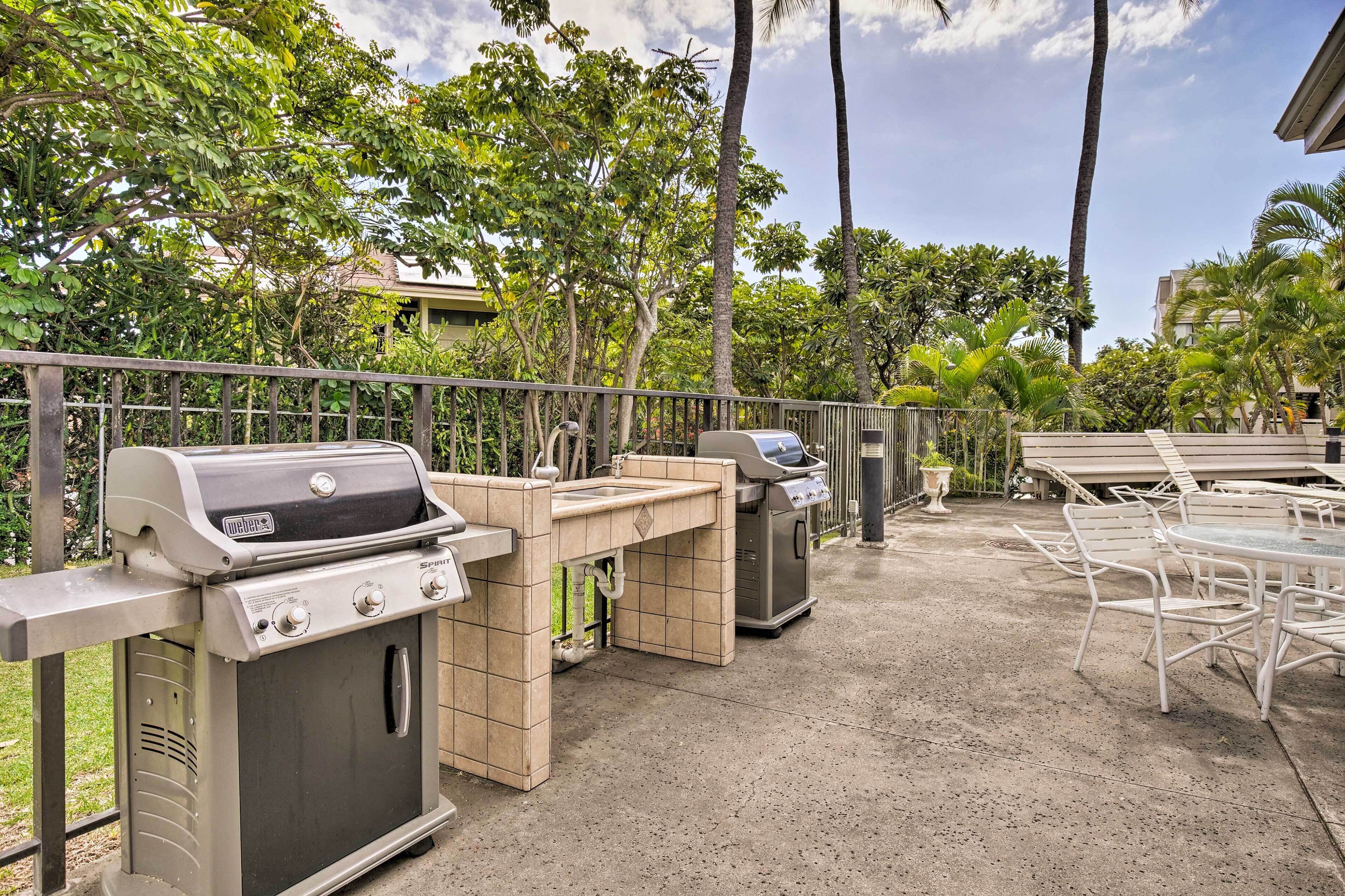 An outdoor patio with a grill, a sink, and a trash can.