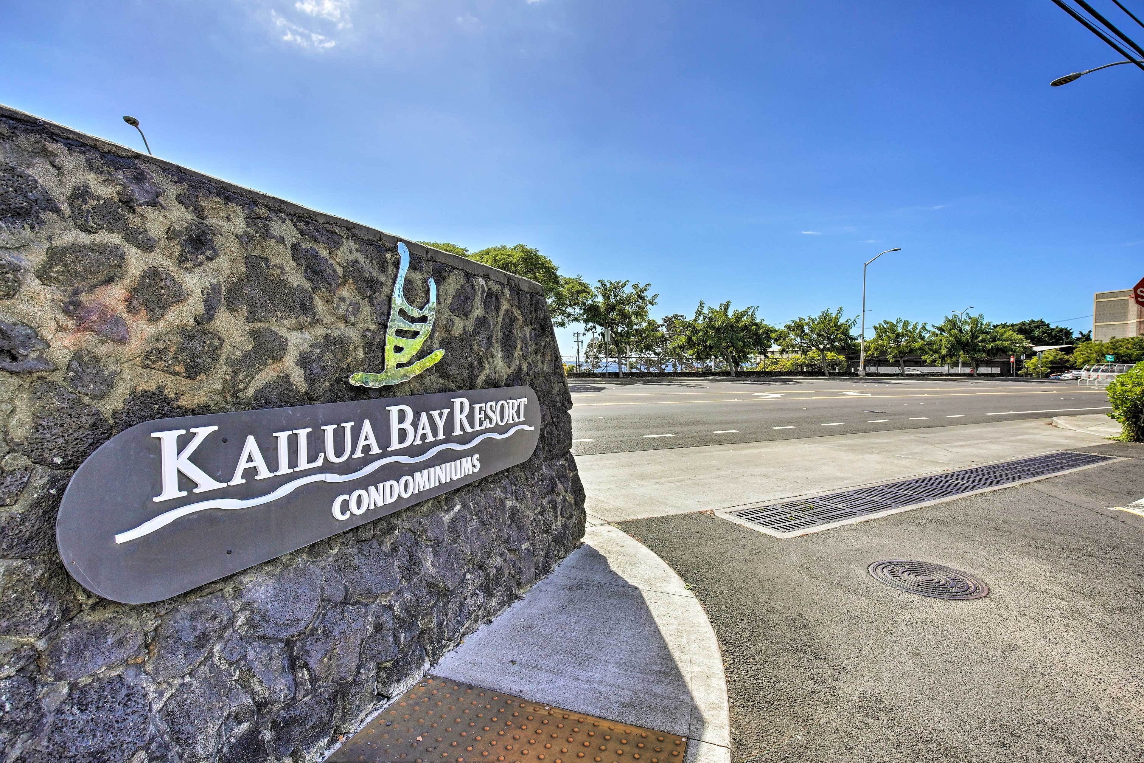 En stenmur med en skylt för Kailua Bay Resort, ett komplex med lägenheter.