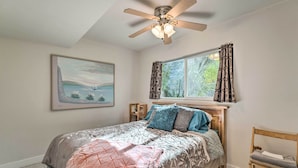 A bedroom with a bed, a ceiling fan, a window with curtains, a chair, and a framed picture on the wall. - 'vegas Oasis' Home w/ Pool & Spa: 7 Miles to Strip (Las Vegas)