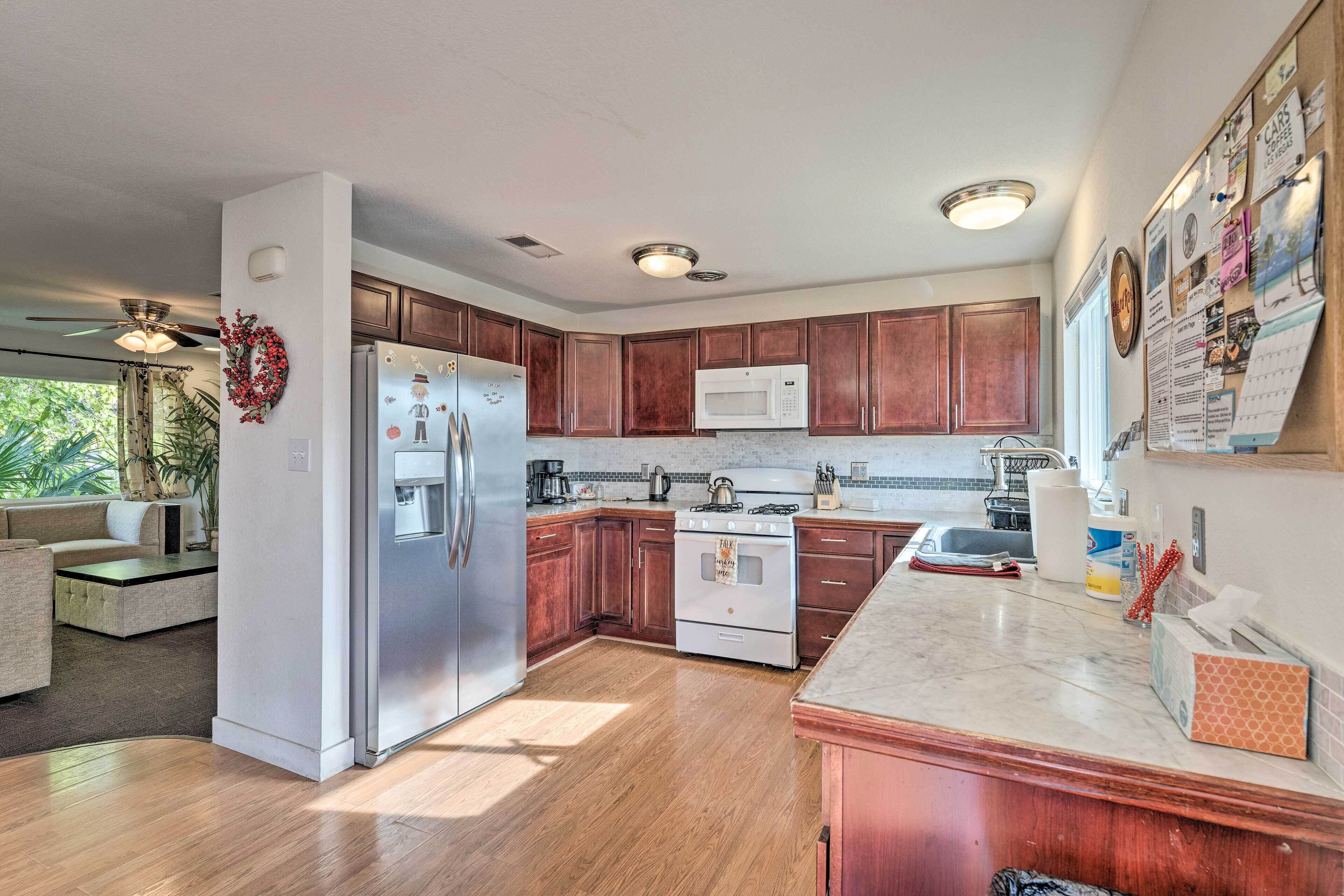A modern kitchen with wooden cabinets, stainless steel appliances, and a marble countertop.