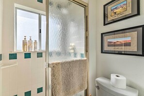 Uma casa de banho com sanita, porta-toalhas, janela e quadros nas paredes.